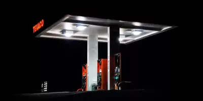 A Gas Station Is Brightly Lit Up At Night, With Its Lights Casting A Glow On The Surrounding Area.